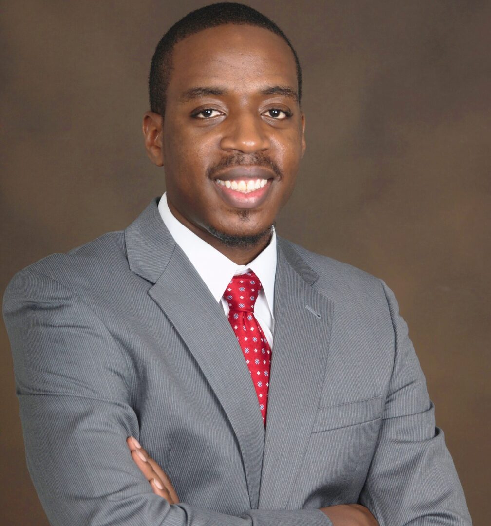 Professional man in a gray suit smiling with arms crossed.